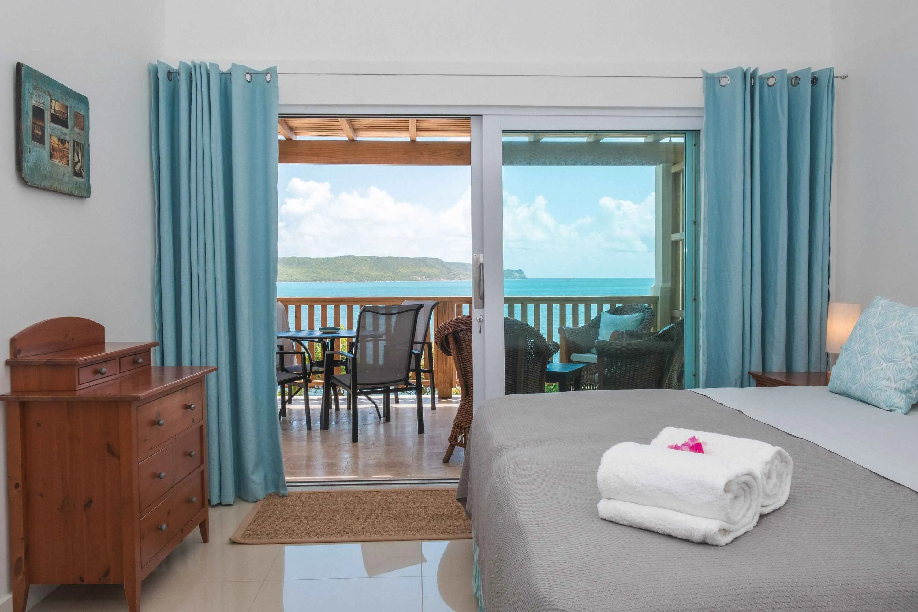 Bedroom with kingsized bed looking out to bay through large glass doors.